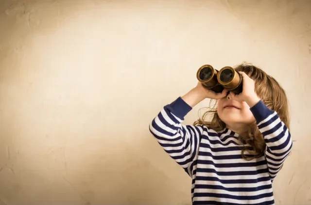 Child in a striped top looking through binoculars