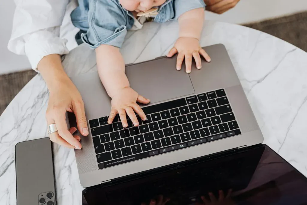 Child’s hands on a laptop keyboard beside an adult
