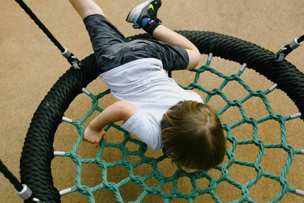 Child hanging upside down on a net swing