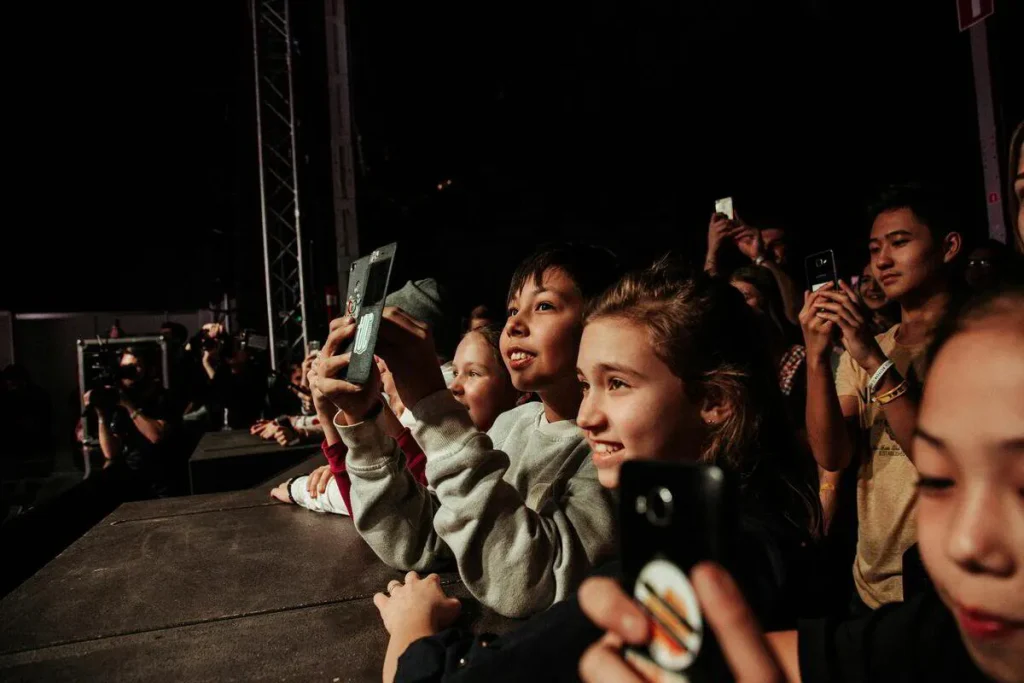 Group of children and teens filming a concert on their phones