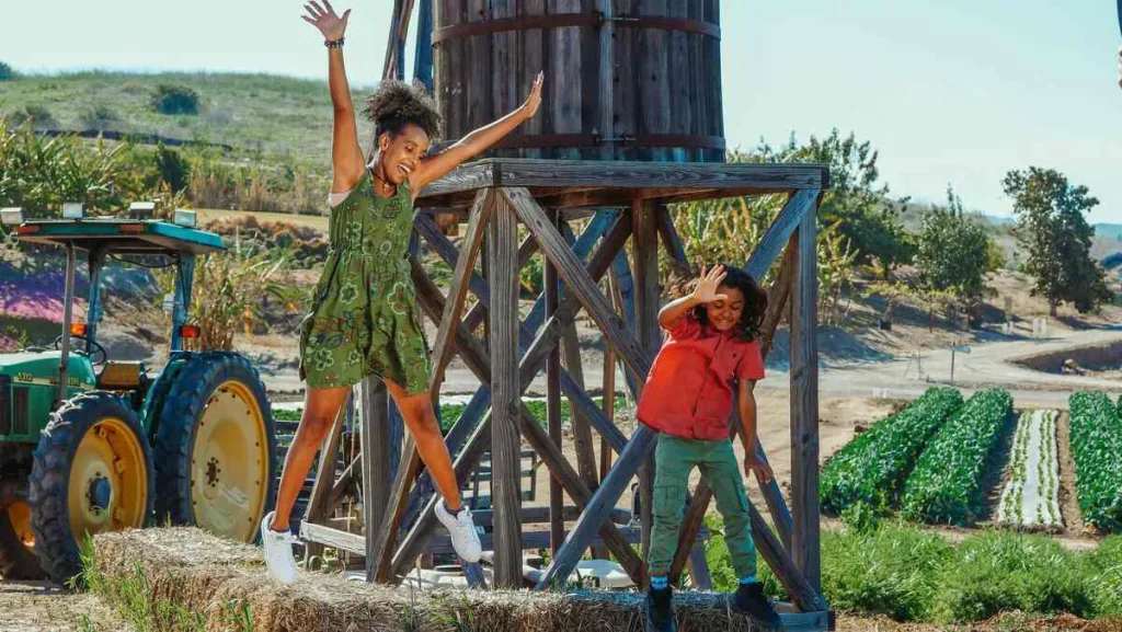 Two children playing and jumping outdoors on a farm