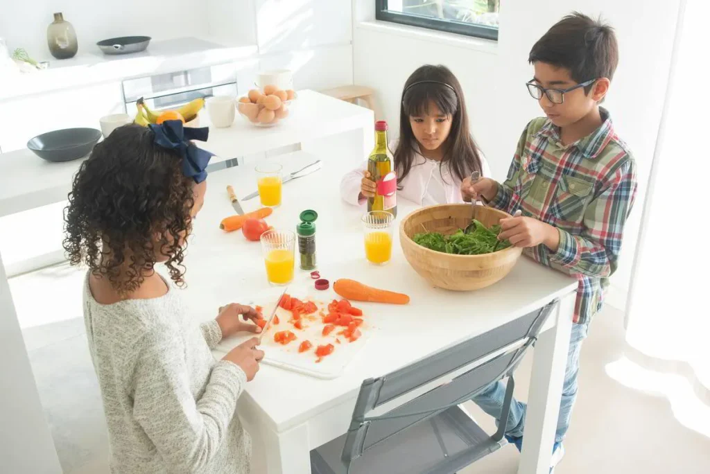 Children preparing vegetables together at the kitchen table