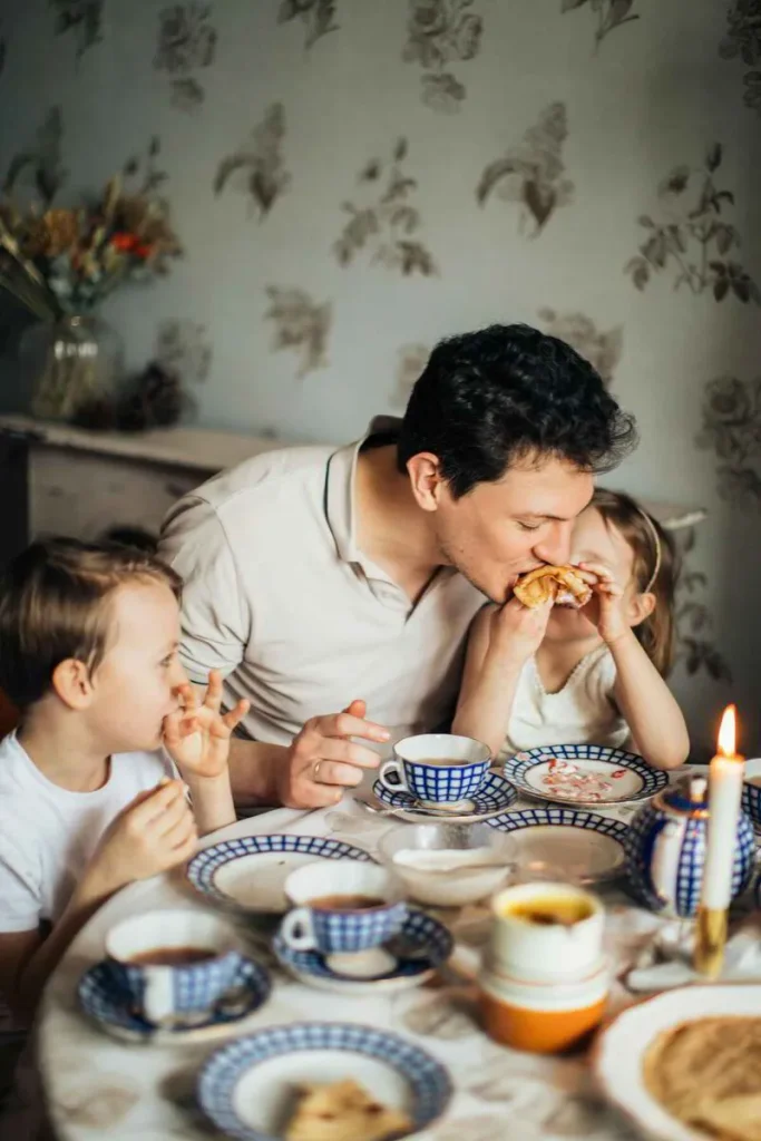 Father and children sharing breakfast around a table with a candle