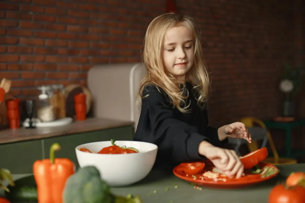 Girl chopping red capsicum and other vegetables in the kitchen