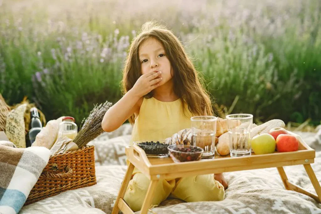 Girl eating a snack from a picnic tray outdoors