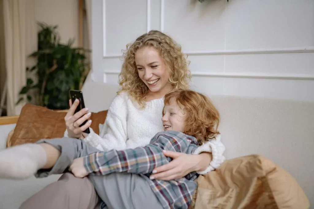 Mother and child cuddling on the sofa while looking at a phone
