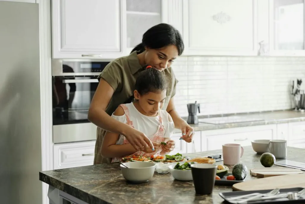 Mother and young daughter preparing food at the kitchen counter