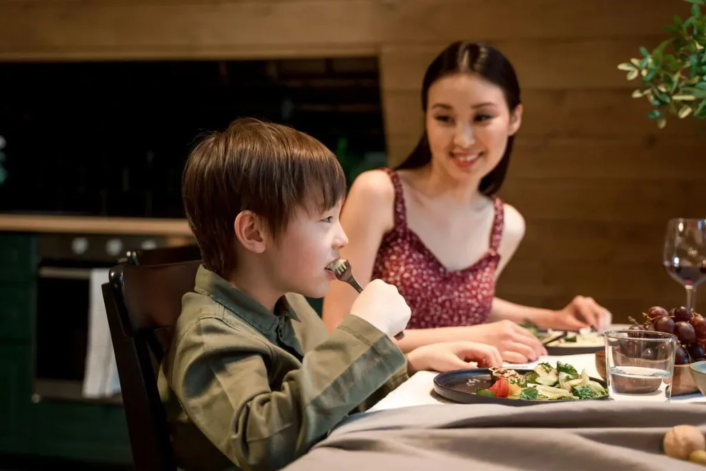 Mother and son smiling at each other over dinner