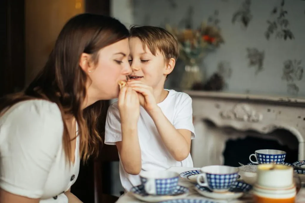 Mother talking quietly with her young son at a table set with tea cups