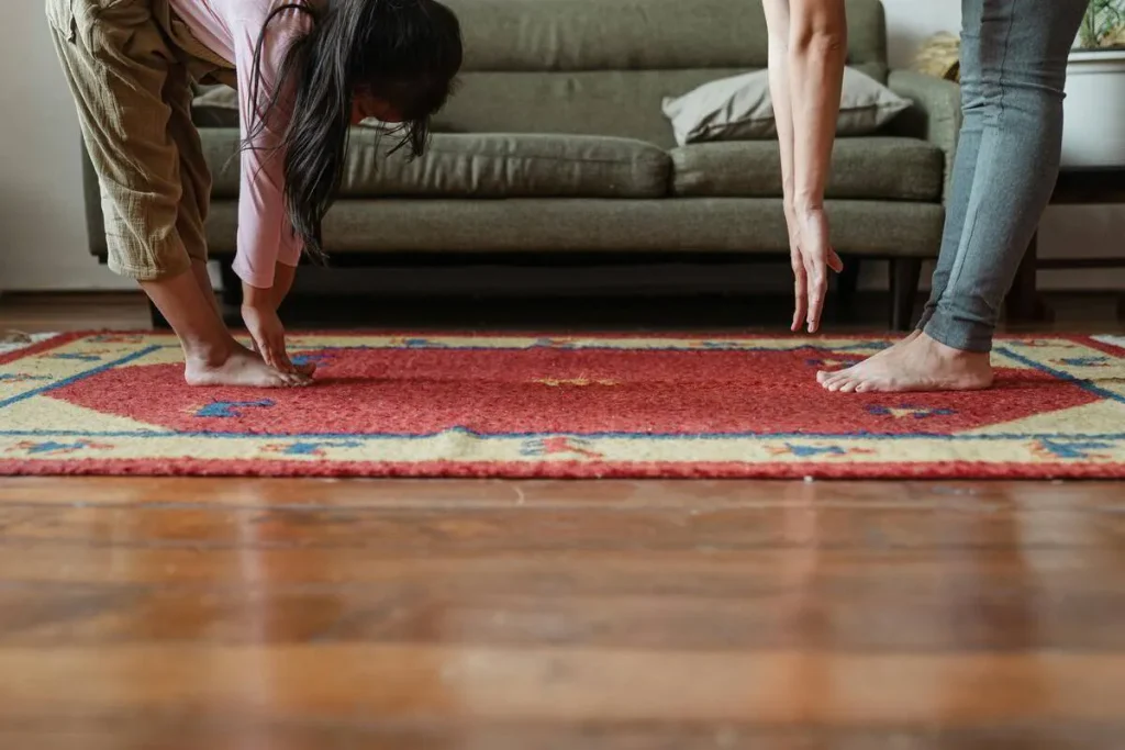 People stretching on a red rug in a living room