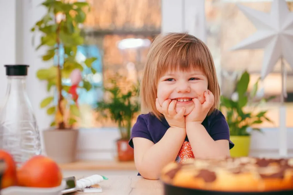 Smiling girl resting her chin on her hands beside a homemade pizza