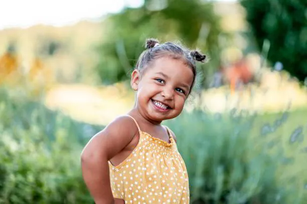 Smiling girl with hair buns in a yellow top outdoors