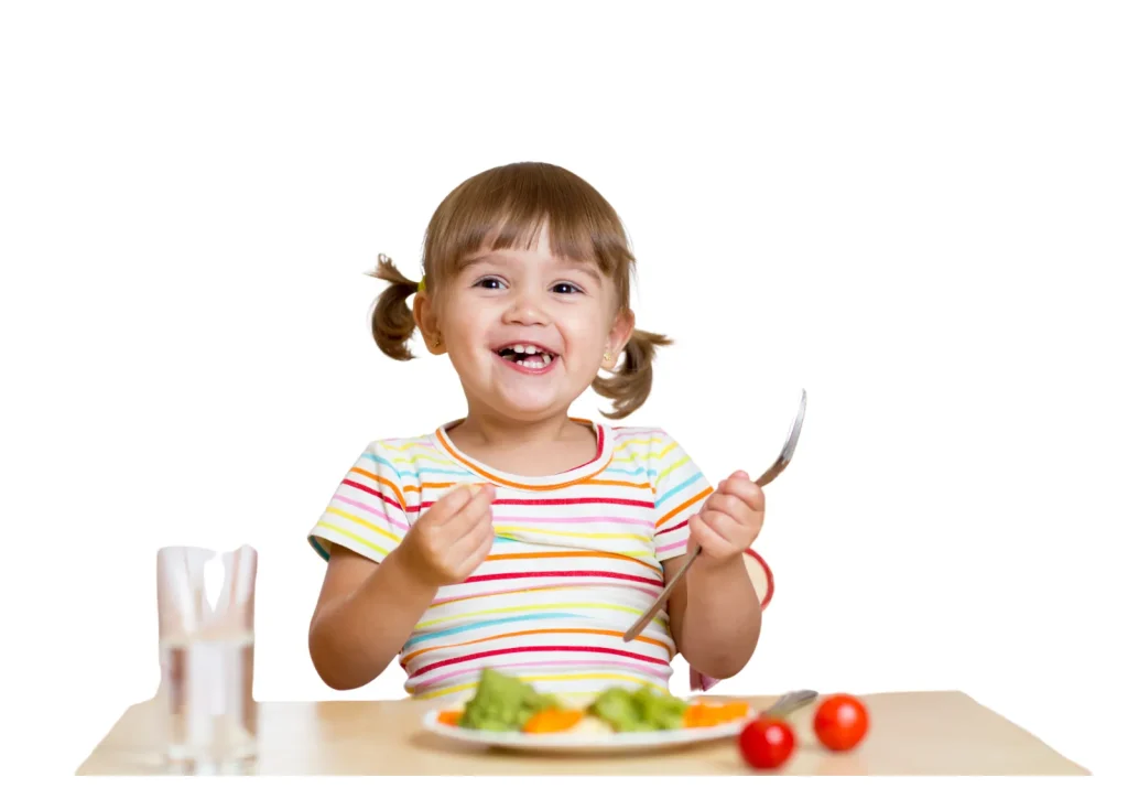 Toddler girl with pigtails eating vegetables with a fork