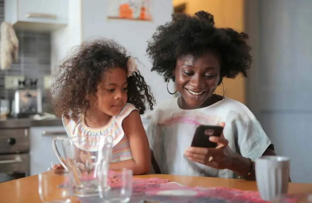 Two girls at the kitchen table looking at a phone